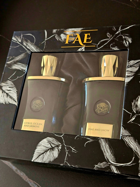 Citrus, Ocean and Jasmine and Pine and Snow bottles inside a black Fae Perfume gift box with white botanical artwork.